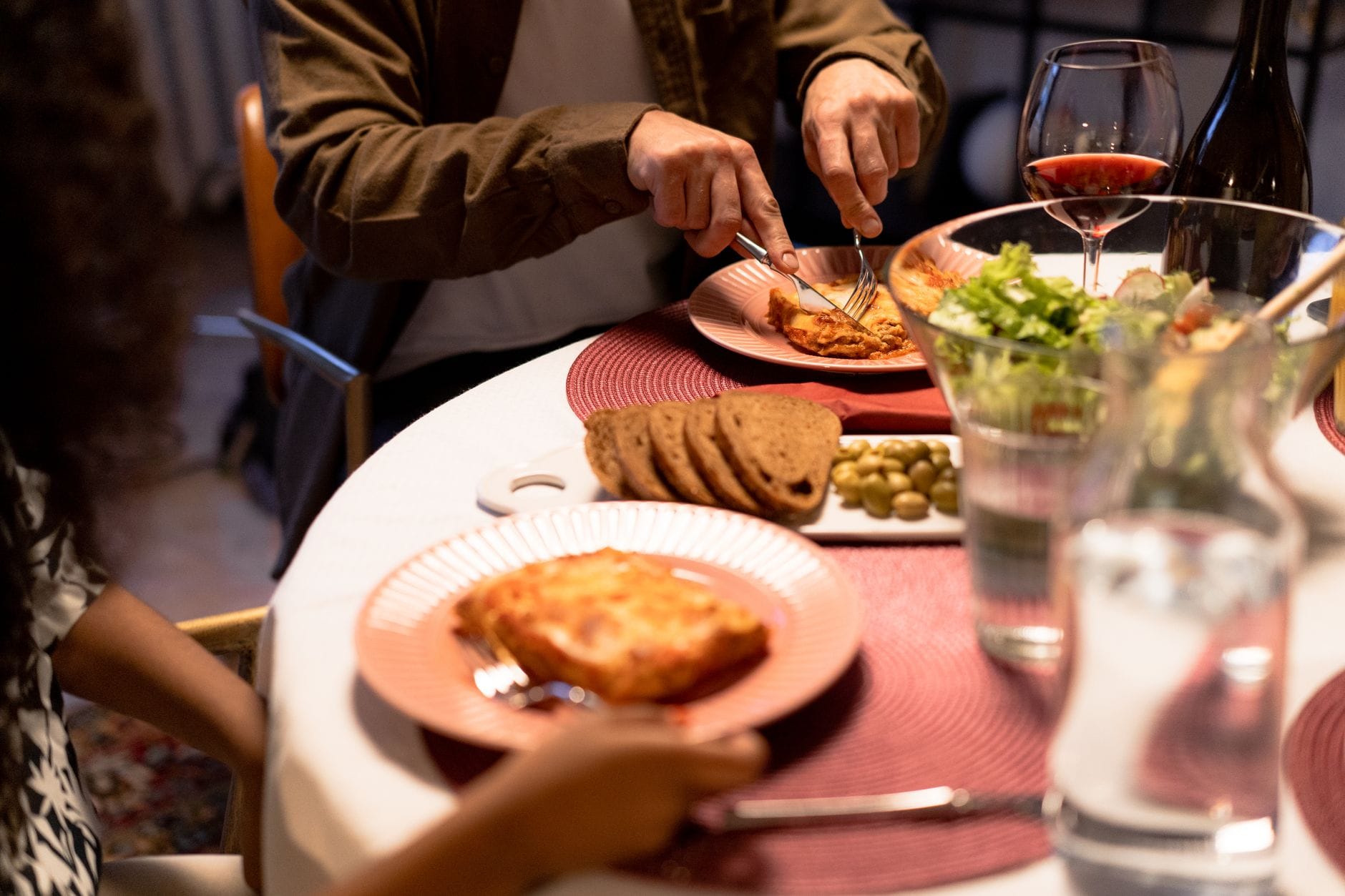 Kolacja przy świecach z lasagne, sałatką i winem na odświętnym stole