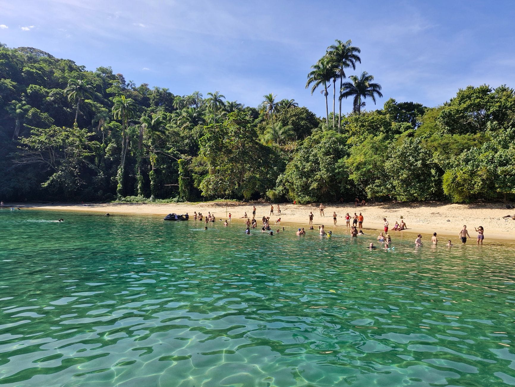 Spokojna plaża na Lomboku z kąpiącymi się ludźmi i zielonym wzgórzem w tle