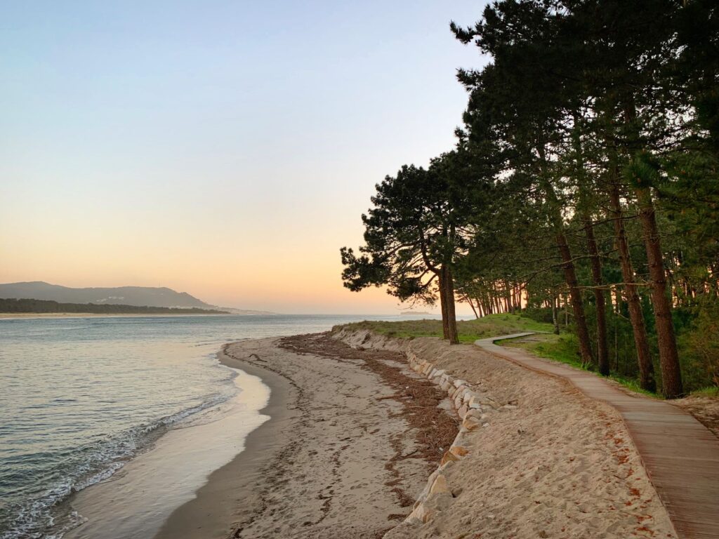 Drewniana kładka przy piaszczystej plaży w Galicji o zachodzie słońca