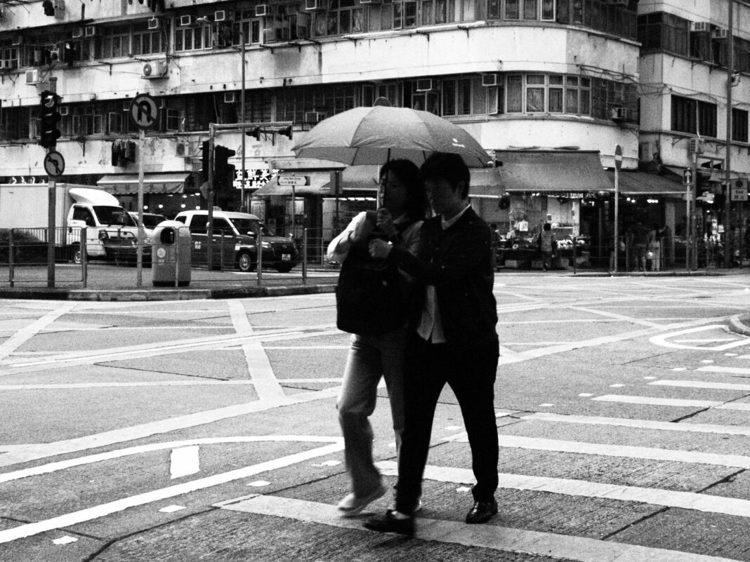Ludzie pod parasolem na ulicy w Hongkongu w deszczu Ludzie pod parasolem na ulicy w Hongkongu w deszczu