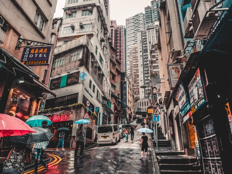 Tłoczna ulica w Hongkongu podczas deszczu, przechodnie z parasolami